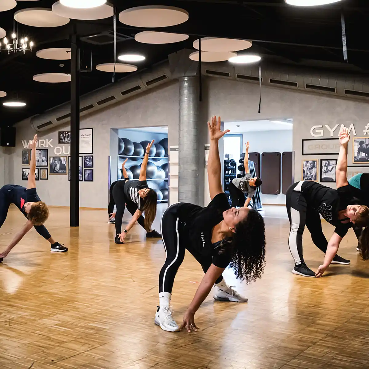 Gruppe im Bewegungskurs beim seitlichen Dehnen im Kursraum des Sport+WellnessPark ALTE ZIEGELEI